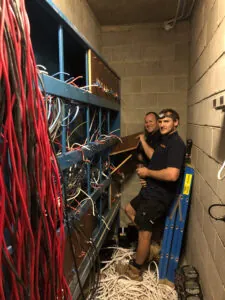 two switchboard electricians working in a large body corporate switchboard to upgrade the power capacity