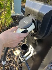 A person grabbing a public Electric Vehicle Charger