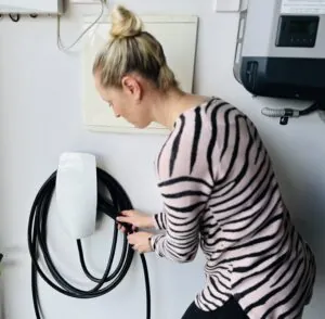 Female homeowner using a personal EV Charger from the wall in their home