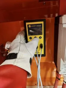 Electrician hand wearing a protective glove is setting up a energy data logger on an apartment switchboard